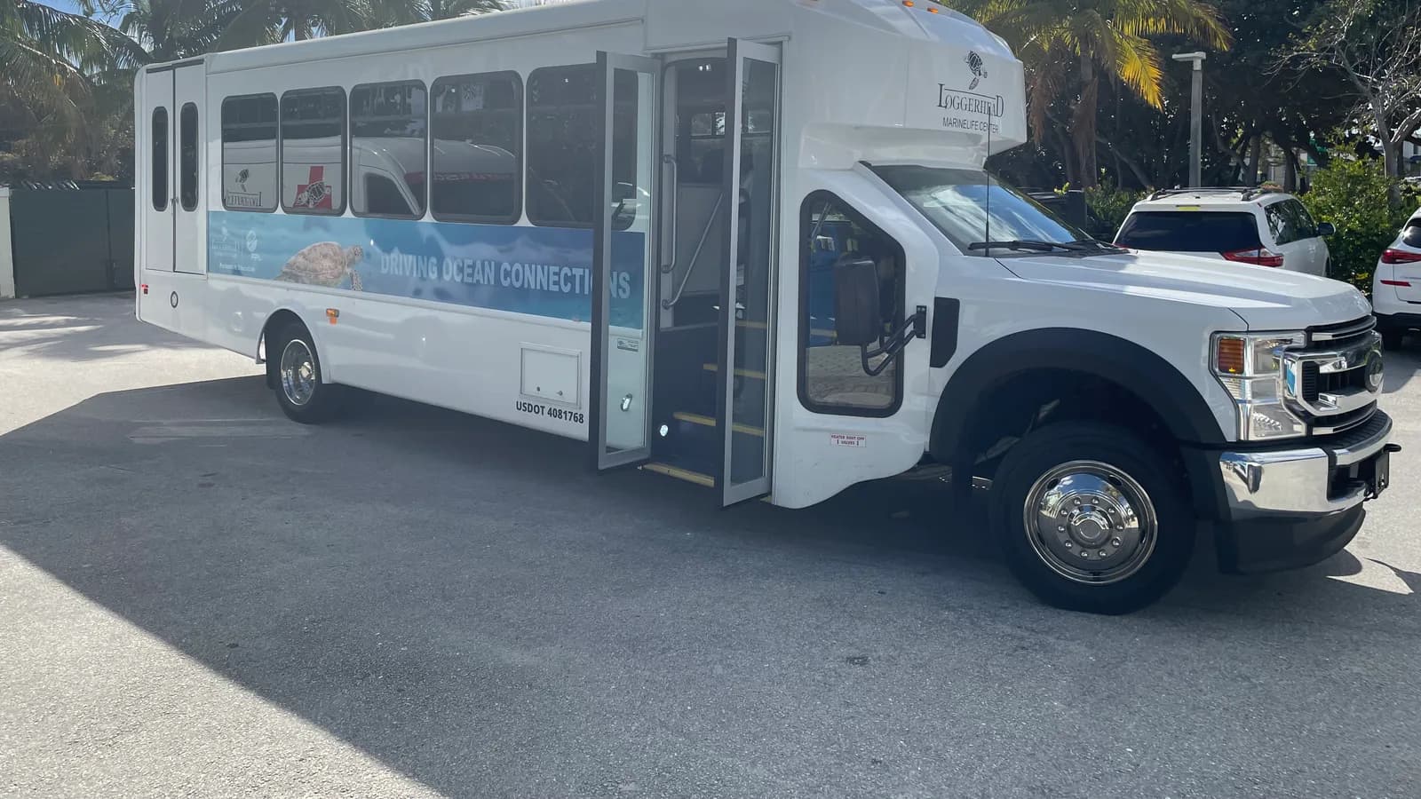 A white shuttle bus with its passenger door open in a parking lot