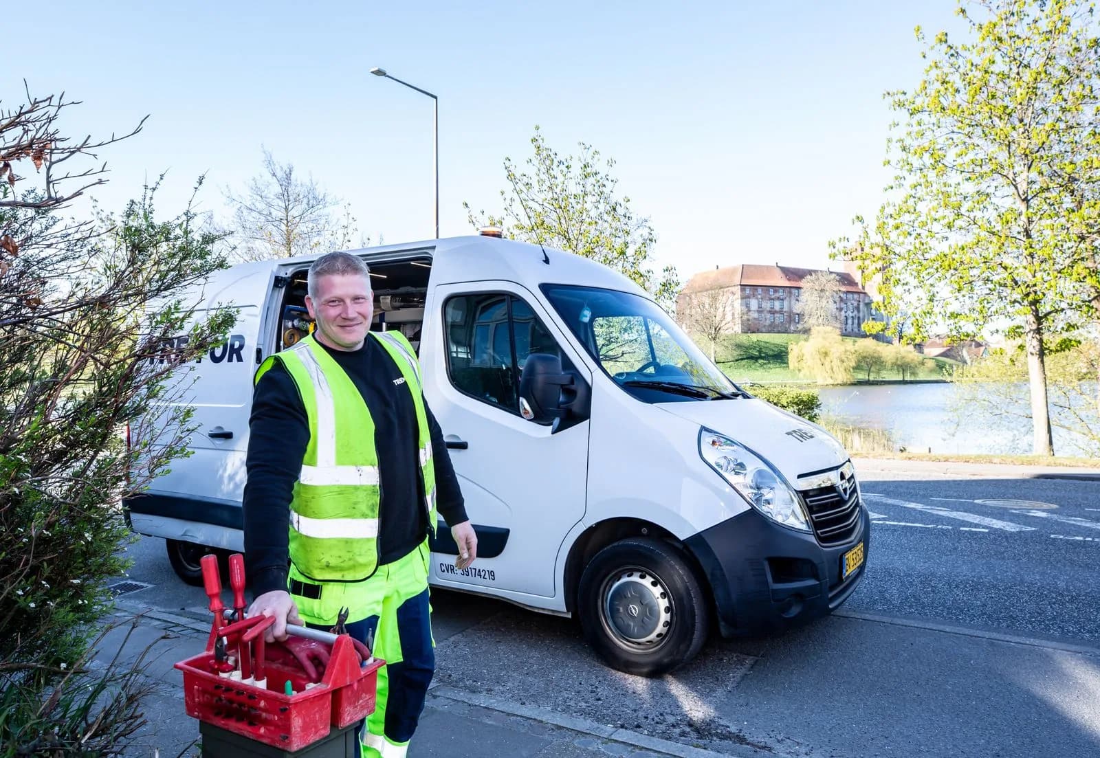 A courier in a high-visibility vest loading crates into a white van