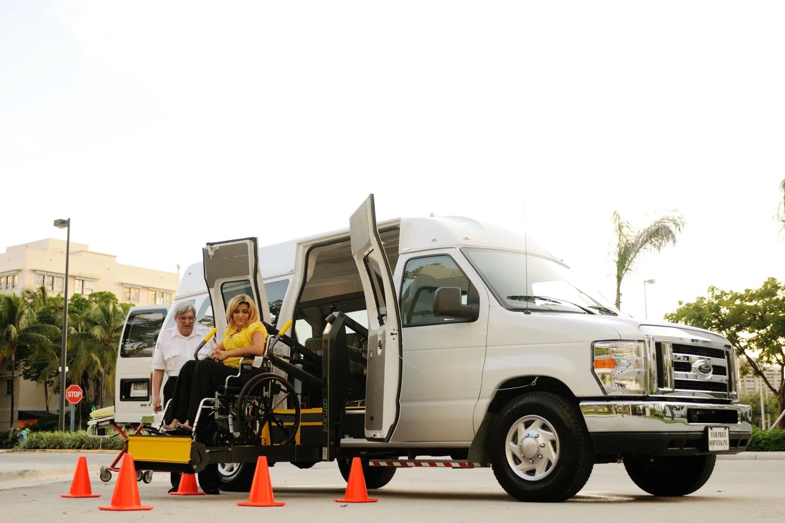 A wheelchair-accessible medical transport van with a driver assisting a passenger