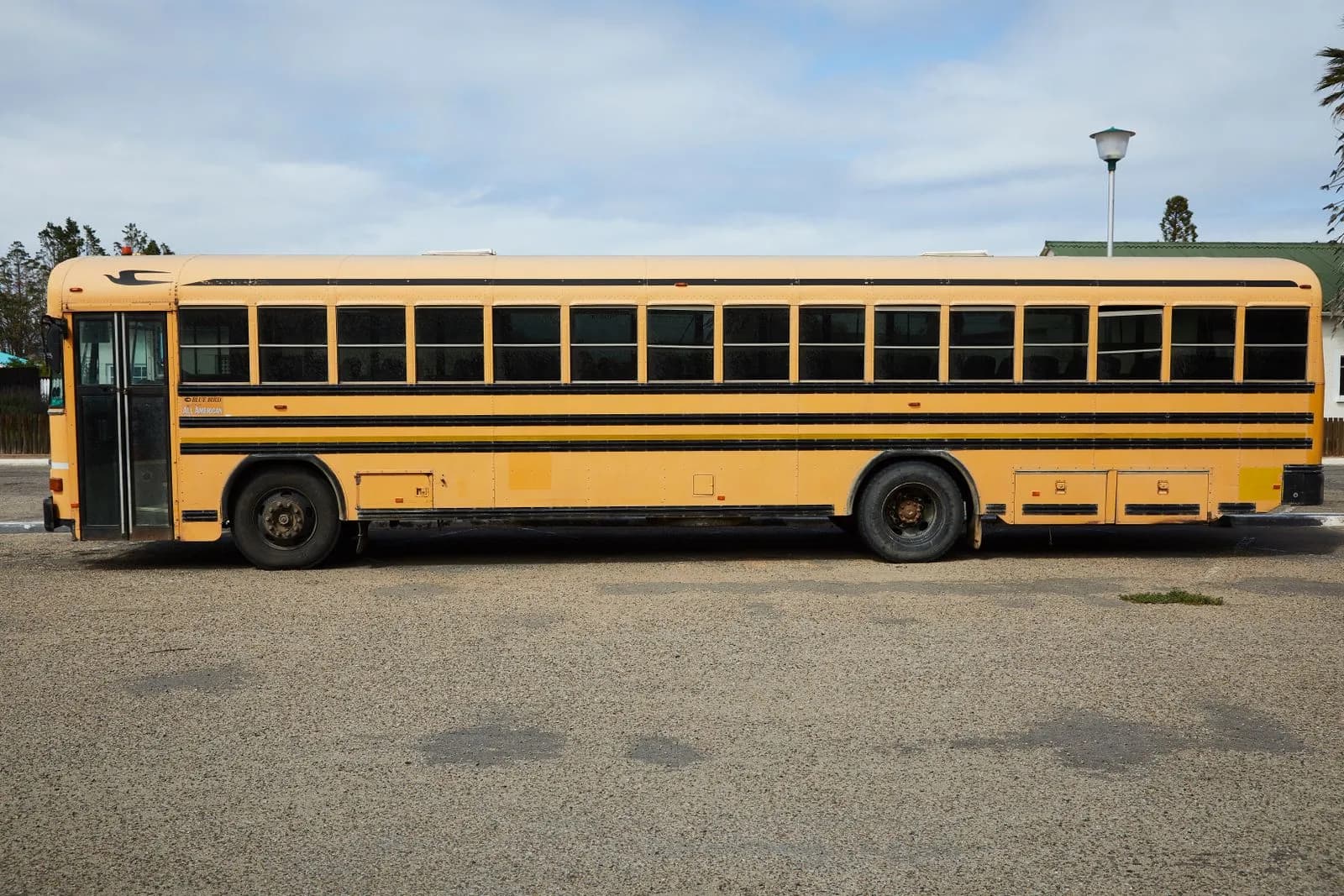A yellow school bus parked in a lot on a cloudy day