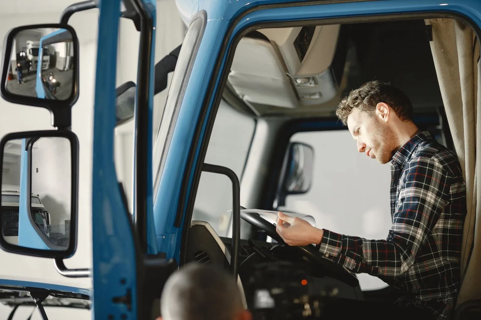 A driver reviewing a checklist inside a commercial vehicle cab